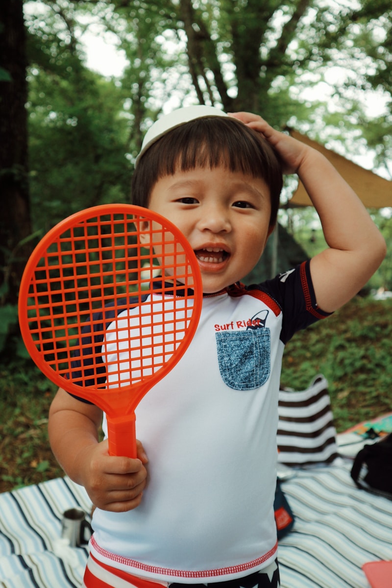 a young boy holding a tennis racquet on top of a blanket