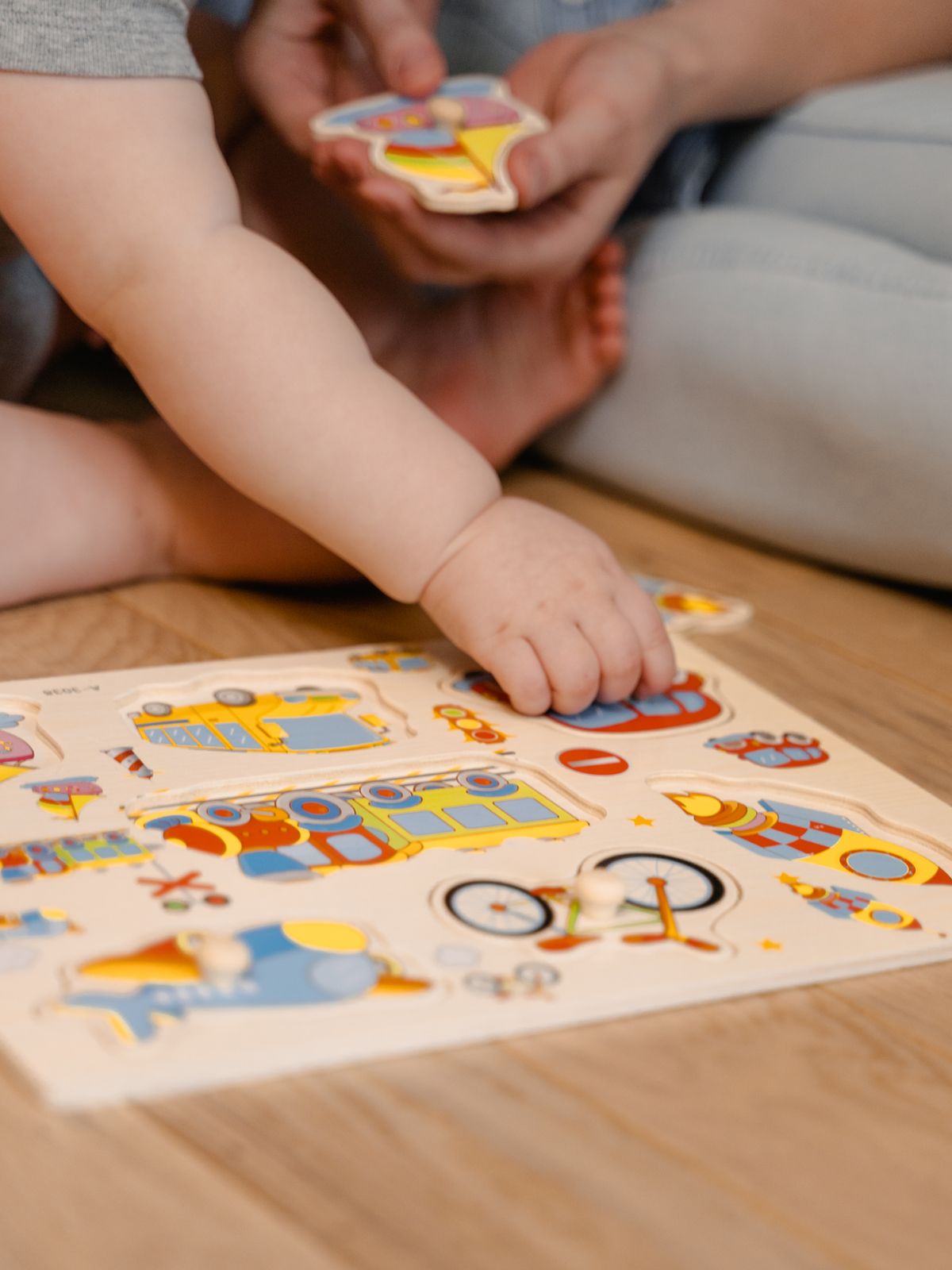 Young child exploring a colorful wooden puzzle with an adult